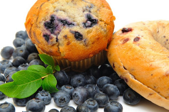 新鲜的蓝莓环绕单蓝莓松饼而且贝果光背景松饼和贝果