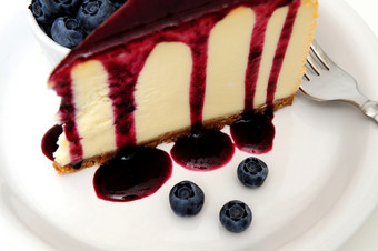 芝士蛋糕与蓝莓酱汁平原芝士蛋糕与蓝莓酱汁倒在的前与新鲜的浆果的板下一个的蛋糕而且超过与薄荷叶