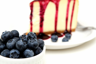 新鲜的蓝莓和芝士蛋糕平原芝士蛋糕与蓝莓酱汁倒在的前与新鲜的浆果的板下一个的蛋糕而且超过与薄荷叶