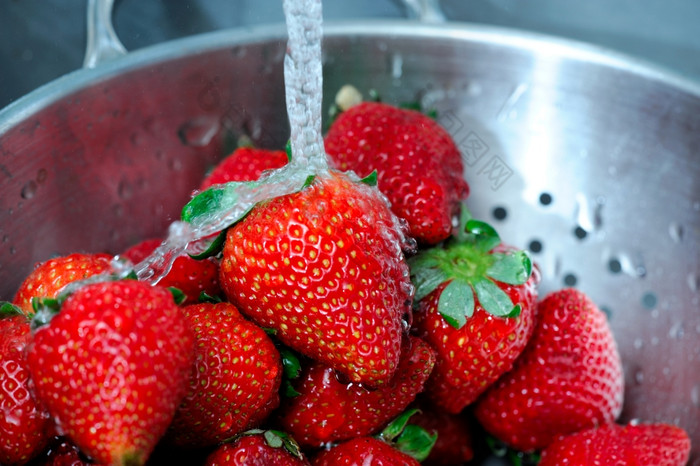 新鲜的草莓新鲜的清晰的水溅从成熟的红色的草莓不锈钢钢滤器与水滴抓住了暂停的空气