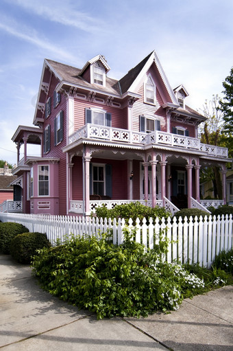 美丽的粉红色的维多利亚时代房子与玄关而且阳台包围白色选栅栏