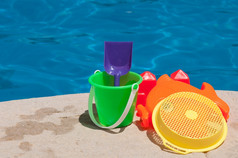 明亮的而且色彩斑斓的孩子们玩具在游泳池边家庭假期概念