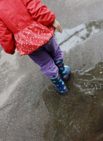 的部分的图像小女孩站向后穿着夹克而且橡胶靴子走通过水坑而且湿沥青
