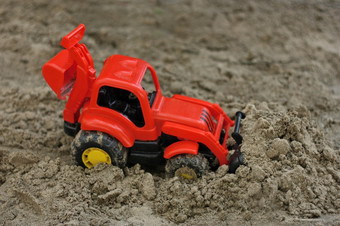 小红色的塑料玩具挖掘机推土机在的沙子玩具被遗忘的的操场上