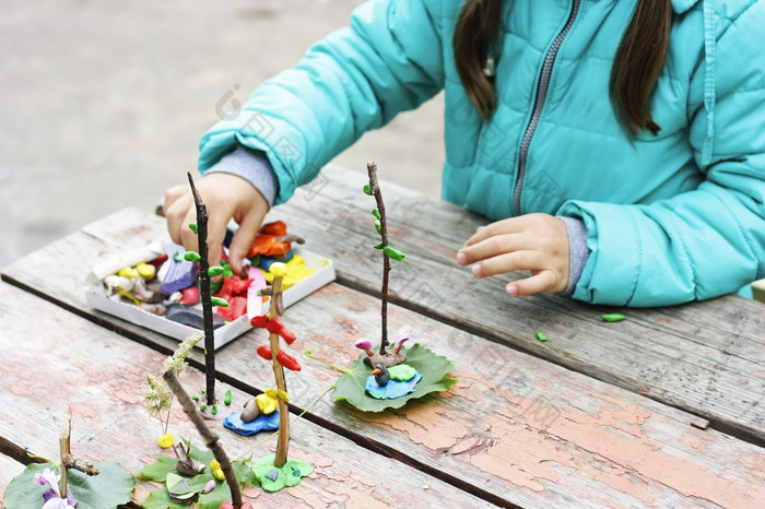 孩子玩在户外的图像部分小孩子玩与橡皮泥的街后面的桃花心木桌子上孩子戏剧与粘土和各种各样的自然材料与不同的形状孩子们雕刻从橡皮泥走