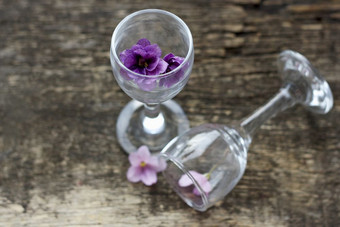 的花是紫罗兰花backgroundthe花的玻璃几小紫罗兰色的花透明的玻璃眼镜散焦眼镜的木表面