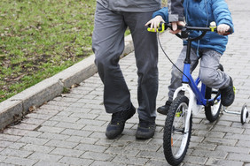 孩子学习骑自行车的父亲走下一个他和支持的
