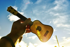 的音乐家持有吉他的天空日落成功概念