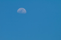 清晰的蓝色的天空与一半月亮的一天时间