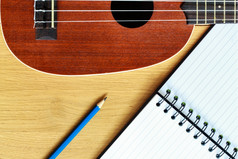 尤克里里琴吉他与空白笔记本而且铅笔