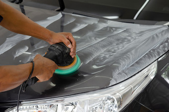 男人。工作为抛光涂层汽车抛光的车将帮助消除污染物的表面的汽车蜡的车表面将导致发光后抛光的车