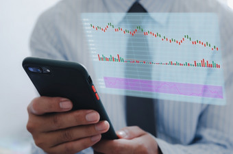 商人使用移动电话分析股票市场和经济增长图表与图标虚拟屏幕业务策略金融和银行数字市场营销