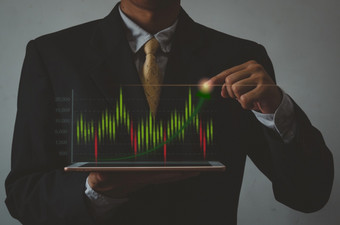 商人持有平板电脑手和图标图股票市场虚拟屏幕投资业务和概念<strong>金融</strong>