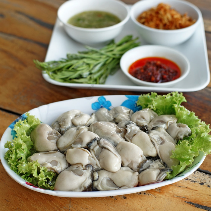 新鲜的牡蛎与一边菜木桌子上图片