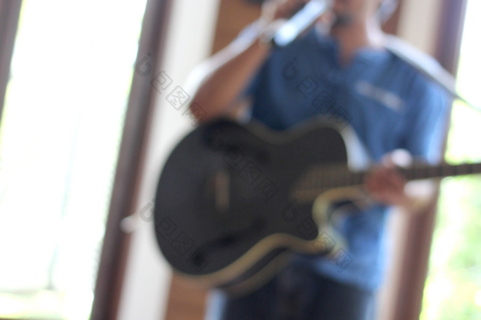 模糊的照片音乐家玩吉他与手持有麦克风模糊的照片音乐家玩吉他