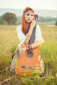 漂亮的国家嬉皮女孩玩吉他草