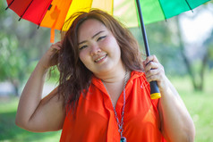 快乐高脂肪的亚洲女人与伞户外公园