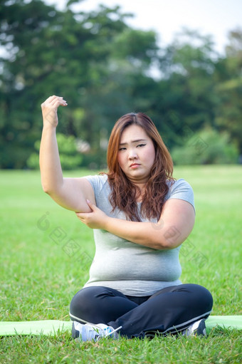 年轻的亚洲脂肪女人检查她的手臂脂肪