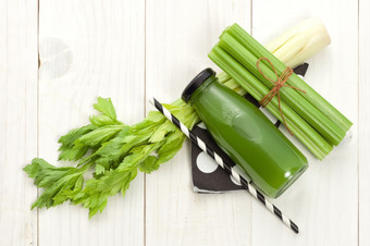 蔬菜汁瓶与芹菜茎白色木背景