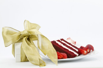 白色盒子包装与黄金丝带特殊的礼物放置下一个片红色的天鹅绒蛋糕新装的与切片草莓