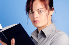 年轻的女人阅读空白书蓝色的背景