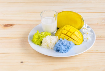 芒果和自然彩色的黏糊糊的大米与椰子牛奶泰国芒果和自然彩色的黏糊糊的大米彩色的蓝色的与露兜树叶提取和彩色的蓝色的与蝴蝶(2008年)花与椰子牛奶木表格泰国甜点