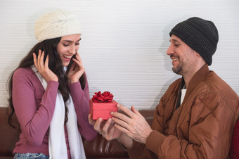 男人。令人惊讶的他的的女朋友与红色的礼物盒子沙发上生活房间夫妇庆祝假期<strong>周年</strong>纪念日生日在一起<strong>首页</strong>