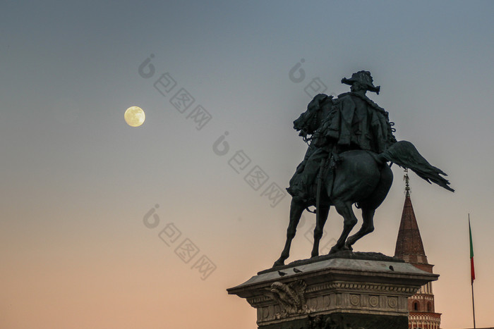 意大利米兰4月在日落的完整的月亮上升前面的纪念碑胜利者以马内利的广场的大教堂米兰胜利雕像广场的大教堂