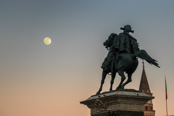 意大利米兰4月在日落的完整的月亮上升前面的纪念碑胜利者以马内利的广场的大教堂米兰胜利雕像广场的大教堂