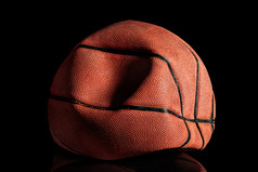 放气和弄皱的老篮球球黑色的背景反射放气和弄皱的老篮球球