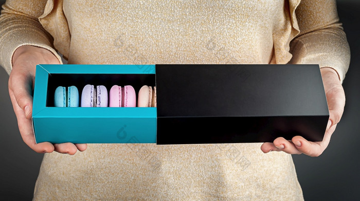 美丽的女手持有五彩缤纷的法国蛋白杏仁饼礼物盒子女孩持有开放盒子与蛋白杏仁饼