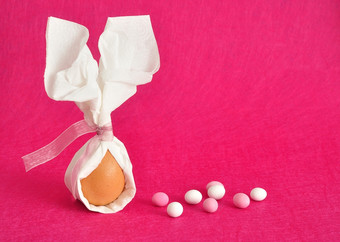 蛋系serviette那看起来就像兔子耳朵为复活节显示与糖果粉红色的背景