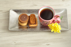 桩饼干与粉红色的杯子填满与咖啡和黄色的花