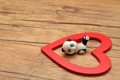 情人节一天陶瓷熊猫小雕像与红色的心内部红色的木心