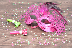 粉红色的化妆舞会面具与鼓风机和五彩纸屑