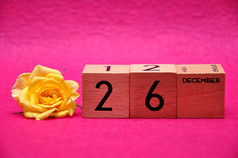 12月木块与黄色的玫瑰粉红色的背景