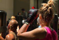 年轻的女人与拳击手套和粉红色的运动服装健身类与冲袋