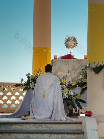 牧师跪下来前面坛与金圣礼显示台户外教堂