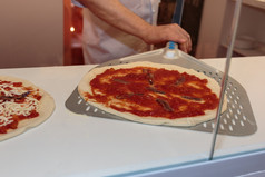 把塞面团为披萨成烤箱与抹刀意大利凤尾鱼披萨准备