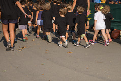孩子们与黑色的衬衫运行的公园与年轻的老师