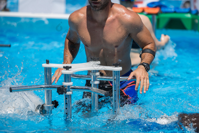 男孩做水有氧运动与金属健身设备内部户外游泳池男孩做水有氧运动与金属健身设备内部户外游泳池