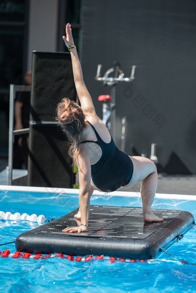 女孩做练习浮动健身席户外游泳池女孩做练习浮动健身席户外游泳池