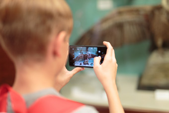 年轻的男孩采取照片与移动电话博物馆塞猛禽年轻的男孩采取照片与移动电话博物馆塞猛禽
