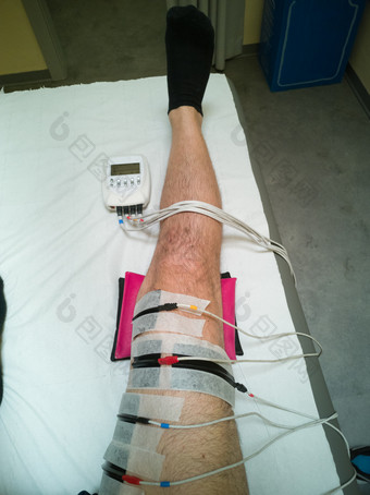 人类腿与肌肉电刺激设备和冰袋在康复练习床上后膝盖手术人类腿与肌肉电刺激设备和冰袋在康复练习床上后膝盖手术
