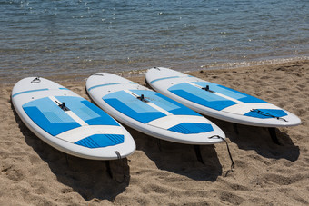 三个白色冲浪板休息的海岸线的海滩三个白色冲浪板休息的海岸线的海滩