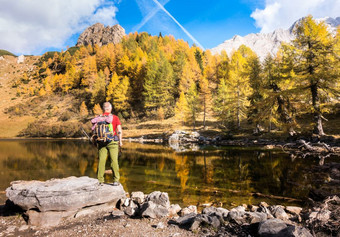 徒步旅行者站岩石欣赏的湖和的秋天颜色景观色彩鲜艳的秋天早....山湖色彩斑斓的秋天景观湖borfaglia绿意盎然意大利