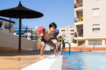 可爱的年轻的男孩摆姿势下一个游泳池而有趣的假期