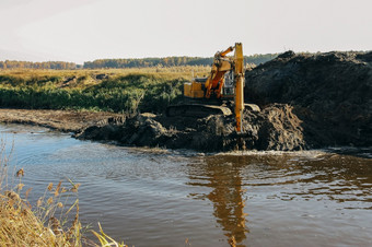 重黄色的挖掘机工作<strong>深化</strong>和清洁小河水运行出从桶