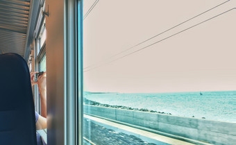 女人采取照片从她的座位而火车移动附近的海