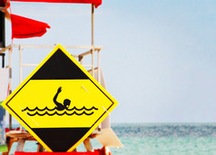 黄色的危险信号描绘溺水游泳运动员的波粗糙的海